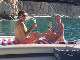 A couple enjoys a toast with cocktails while relaxing on the deck of a yacht, surrounded by stunning coastal scenery — perfect for romantic getaways or celebrations.