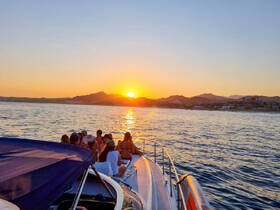 A vibrant sunset view with a group of friends enjoying their time on a boat, capturing the essence of a perfect evening on the water.