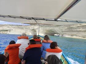 A group of guests enjoys a scenic boat ride along a stunning coastline, capturing the beauty of the cliffs and crystal-clear waters.
