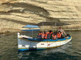 A lively group enjoys a boat ride through a stunning coastal cave, showcasing the beauty of nature and adventure on the water.
