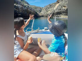 Two children enjoy snacks while exploring a scenic coastline from their boat, capturing the joy of adventure on the water.