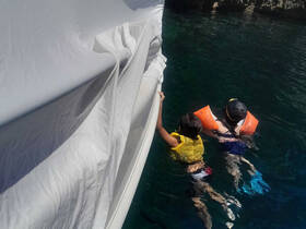 Two children enjoy swimming in clear waters while wearing life jackets, showcasing a fun and safe water adventure.