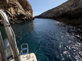 A scenic view of a boat navigating through a narrow waterway surrounded by stunning rocky cliffs, showcasing the beauty of coastal exploration.