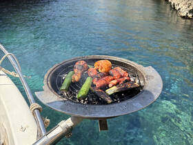 A close-up of a grill with delicious meats and vegetables sizzling on board, perfect for a fun day on the water.