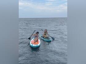 Two friends enjoy paddleboarding in the ocean, showcasing a fun and active day on the water.
