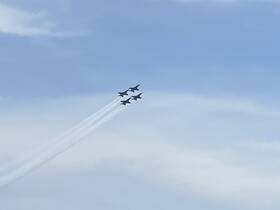 A formation of jets performing aerial maneuvers against a clear sky, showcasing the excitement of an airshow.