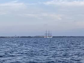 A majestic sailing ship navigates through calm waters, showcasing its impressive sails against a serene backdrop.