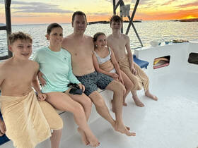 A family enjoys a beautiful sunset aboard a boat, capturing a memorable moment together on the water.