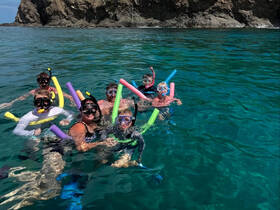 A joyful group enjoys snorkeling in crystal-clear waters, showcasing a fun family adventure in a beautiful marine setting.