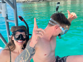 A couple excitedly prepares for snorkeling in crystal-clear waters, showcasing the thrill of underwater adventures.