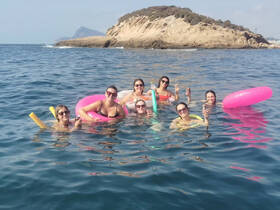 A lively group of friends enjoys a fun day in the water, floating on colorful mats and sipping drinks — the perfect way to celebrate summer adventures.