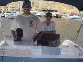 Two individuals are seated at the helm of a boat, showcasing the interior space and equipment, perfect for navigating the waters.