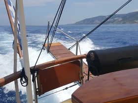 A scenic view from the deck of a boat cruising through open waters, showcasing the vessel's structure and the beautiful coastline in the background.