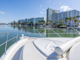 A stunning view from the bow of a yacht, showcasing a serene waterfront lined with palm trees and modern buildings — perfect for luxury cruising and sightseeing.