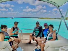 A cheerful group enjoys a day on a pontoon boat, surrounded by stunning turquoise waters — perfect for a fun-filled boating adventure.