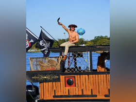 A lively pirate-themed scene featuring a man in costume holding a sword on a boat, showcasing the fun and adventurous spirit of water activities.