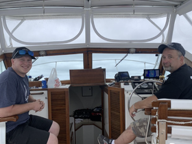 Two men relax in the helm of a boat, showcasing the interior cabin and navigation equipment — perfect for a day out on the water.
