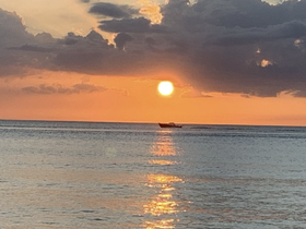 A serene sunset view featuring a boat silhouetted against the vibrant orange sky, creating a picturesque scene perfect for tranquil evenings on the water.