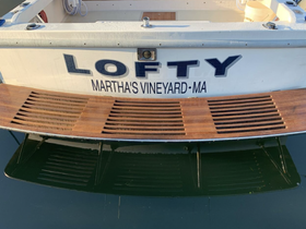 The stern view of the boat named 'Lofty' docked in Martha's Vineyard, showcasing its sleek design and wooden accents.