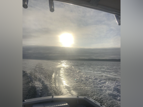 A serene view of the sun setting over calm waters, captured from the deck of a boat — perfect for showcasing tranquil boating experiences.