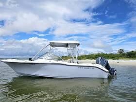 A sleek Key West boat is docked in shallow waters, showcasing its elegant design against a backdrop of blue skies and greenery — perfect for fishing or leisure outings.