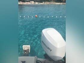 A close-up view of a Mercury outboard motor on a boat, with crystal-clear turquoise waters and a beach in the background, perfect for showcasing boating adventures.