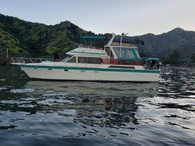 A beautiful side view of a yacht docked in calm waters, surrounded by lush green hills — perfect for scenic boating adventures.