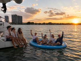 A lively group enjoys a sunset celebration on a floating mat, capturing the essence of fun and relaxation on the water.
