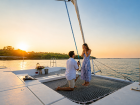 A romantic sunset proposal aboard a yacht, capturing a couple's special moment against a stunning backdrop of golden hues and serene waters.