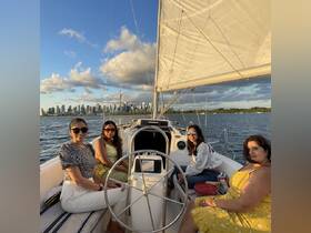 A group of friends enjoys a sailing trip with a stunning city skyline in the background, perfect for memorable outings on the water.