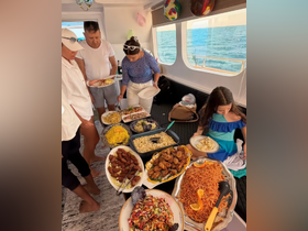 Guests enjoy a lavish spread of food inside the boat, showcasing a variety of dishes perfect for onboard dining experiences.