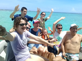 A joyful group of friends and family celebrate on a boat in vibrant turquoise waters, capturing the essence of fun and adventure on the ocean.