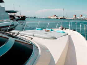 A stunning view of a yacht's deck with sunbathing cushions, set against a picturesque harbor backdrop — perfect for relaxation and enjoying the sea breeze.