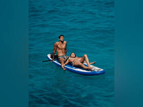 A couple enjoys a relaxing moment on a paddleboard in crystal-clear waters, perfect for sunbathing and water adventures.