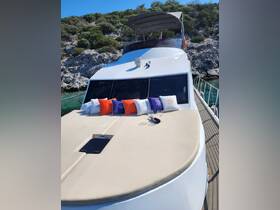 A beautifully arranged lounge area on the front deck of a yacht, featuring colorful cushions and wine glasses, perfect for relaxing in style while enjoying the scenic views.