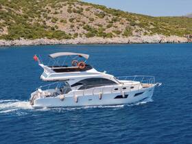 A stunning yacht glides through crystal-clear waters, showcasing its elegant design against a backdrop of lush greenery and rocky coastline.