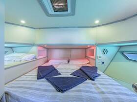 Cozy interior cabin of a boat featuring neatly arranged bedding and ambient lighting, perfect for a comfortable overnight stay on the water.