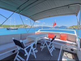 A cozy lounge area on a boat featuring comfortable seating and a table, perfect for relaxing while enjoying scenic views of the turquoise waters and surrounding islands.