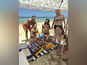 A cheerful group enjoys a beach day with a spread of delicious snacks, perfect for a fun-filled celebration under the sun.