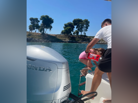 A child prepares to jump into the clear waters while an adult assists from the boat, capturing a joyful moment of family fun on the water.