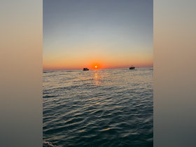 A stunning sunset over the ocean with boats silhouetted against the vibrant sky, perfect for capturing the beauty of a tranquil evening on the water.