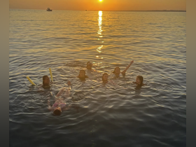 A joyful group enjoys a sunset swim in the ocean, creating unforgettable memories during their boating adventure.