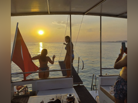 A group of friends enjoys a stunning sunset on a boat, capturing the moment with laughter and joy — perfect for memorable summer outings.