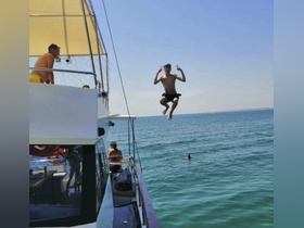 A young boy joyfully jumps off a boat into the clear blue waters, capturing the essence of summer fun and adventure on the water.