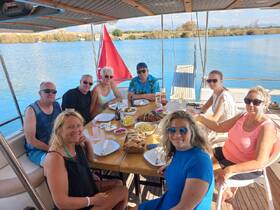 A cheerful group enjoys a delicious meal aboard a boat, surrounded by stunning water views — perfect for memorable gatherings and celebrations on the water.