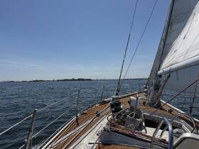 A stunning view from the deck of a sailboat, showcasing the vessel underway against a clear blue sky and shimmering water — perfect for sailing enthusiasts.