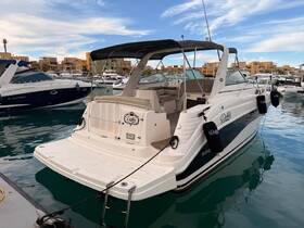 A sleek yacht named 'Debbie' docked in a marina, showcasing its elegant design against a backdrop of colorful buildings.