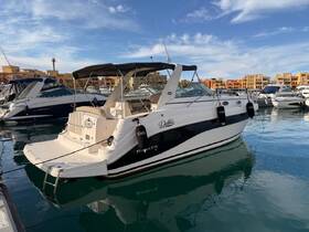 A sleek yacht named 'Debbie' docked in a marina, showcasing its elegant design against a backdrop of colorful buildings.