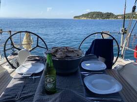 A beautifully set table on a sailboat featuring grilled food and drinks, perfect for enjoying a meal while taking in the stunning ocean views.