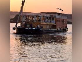 A beautifully crafted boat glides through the water at sunset, showcasing its unique design and serene surroundings — perfect for evening cruises.